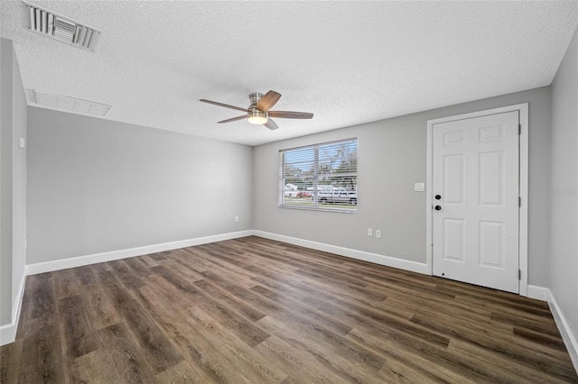 empty room featuring ceiling fan, a textured ceiling, dark wood-style flooring, visible vents, and baseboards