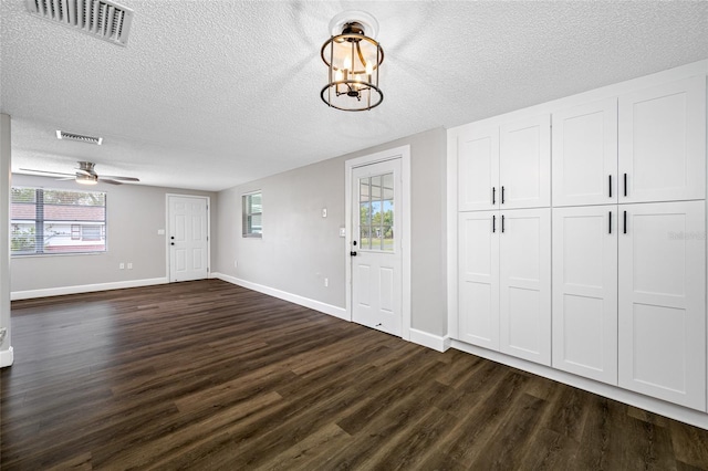 entryway featuring a textured ceiling, dark wood-style flooring, visible vents, and baseboards