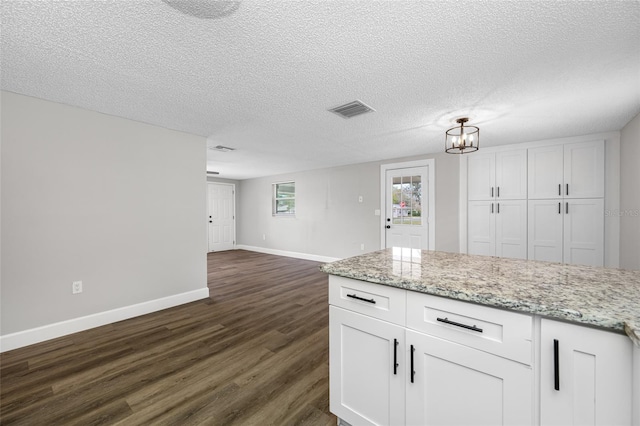 kitchen featuring visible vents, open floor plan, dark wood-type flooring, light stone countertops, and white cabinetry