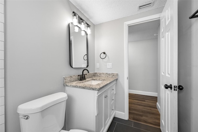 bathroom featuring visible vents, toilet, tile patterned floors, a textured ceiling, and vanity