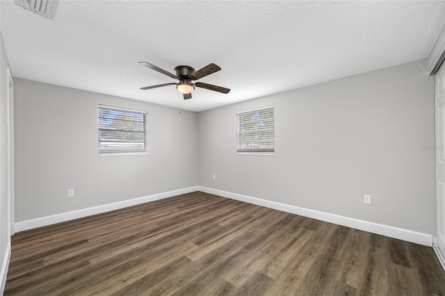 spare room featuring dark wood-style floors, visible vents, plenty of natural light, and baseboards