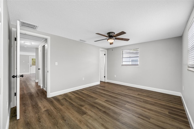 unfurnished room featuring baseboards, a textured ceiling, visible vents, and dark wood-style flooring