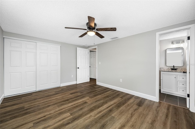 unfurnished bedroom with dark wood-style floors, a textured ceiling, visible vents, and a closet