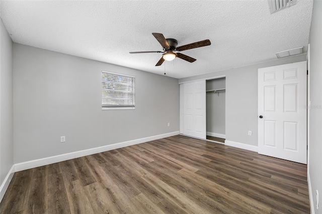 unfurnished bedroom with a closet, visible vents, dark wood finished floors, and baseboards