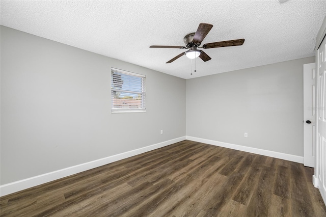 empty room with a textured ceiling, dark wood finished floors, and baseboards