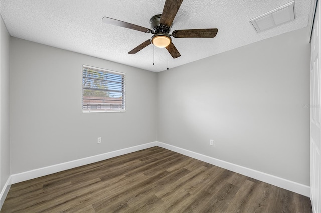 spare room with dark wood-style floors, a textured ceiling, visible vents, and baseboards