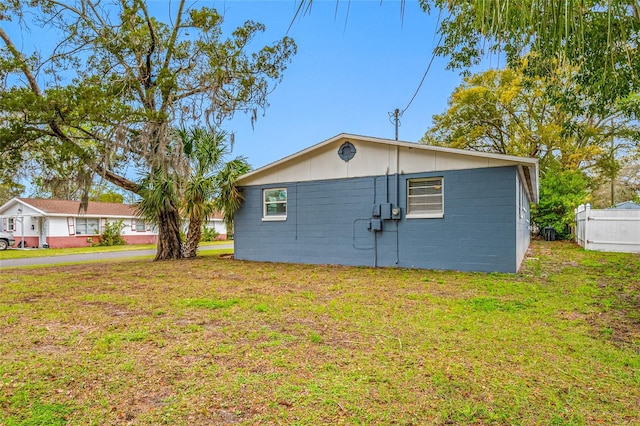 view of home's exterior featuring concrete block siding and a yard