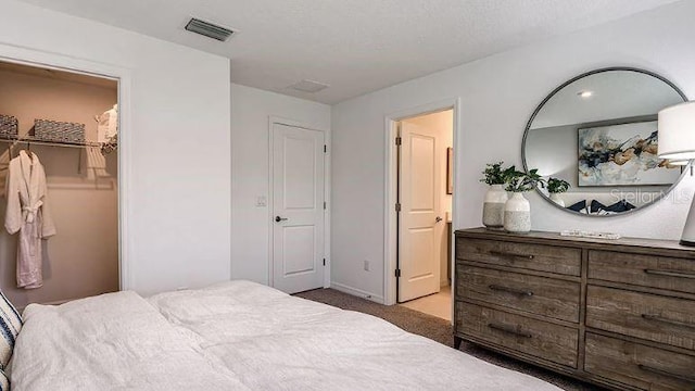 bedroom featuring carpet floors, a spacious closet, and visible vents