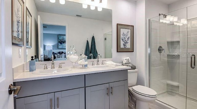 bathroom with a sink, a shower stall, toilet, and ensuite bathroom