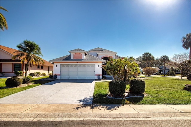 view of front of property with a garage, stucco siding, concrete driveway, and a front lawn