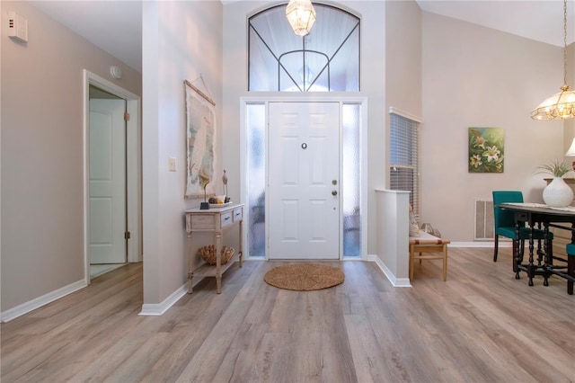 entryway featuring an inviting chandelier, wood finished floors, and baseboards