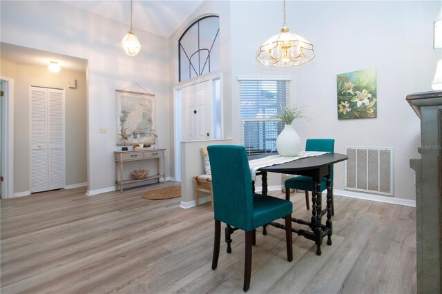 dining space featuring visible vents, baseboards, a high ceiling, and wood finished floors