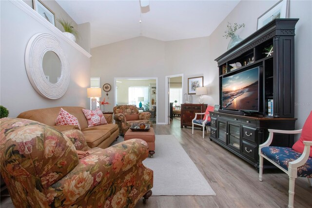 living area with high vaulted ceiling, light wood-type flooring, and ceiling fan