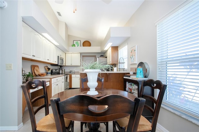 dining area featuring light tile patterned floors, visible vents, baseboards, and vaulted ceiling