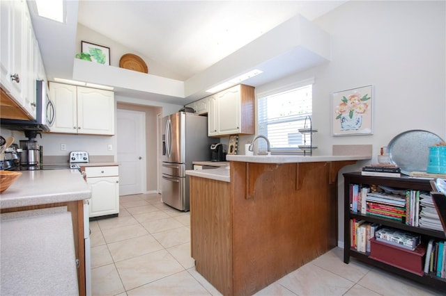 kitchen with a peninsula, a breakfast bar area, light tile patterned floors, and lofted ceiling