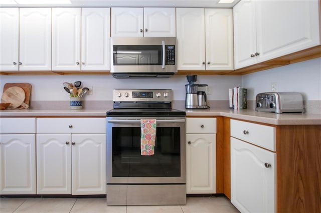 kitchen featuring light tile patterned floors, appliances with stainless steel finishes, white cabinets, and light countertops