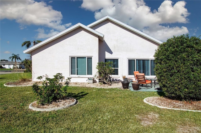 back of house with a yard, a patio, and stucco siding