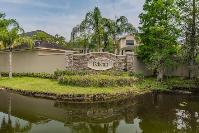 community sign featuring a water view and a yard