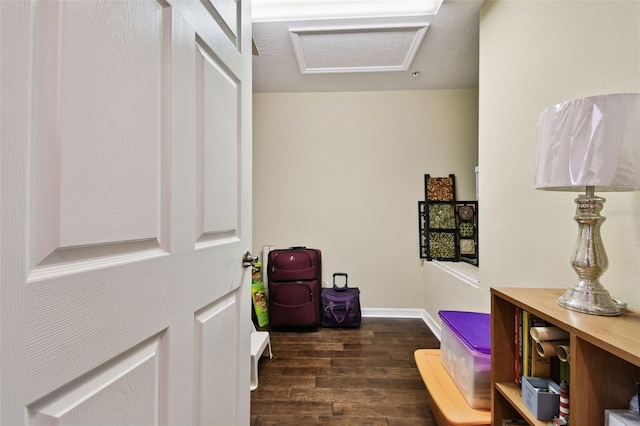 interior space featuring attic access, baseboards, and wood finished floors