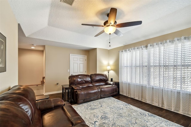 living area featuring a tray ceiling, visible vents, dark wood finished floors, and a textured ceiling