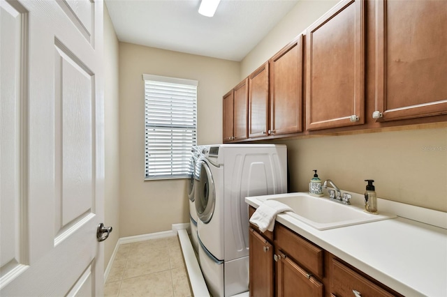 laundry area with washing machine and clothes dryer, cabinet space, light tile patterned flooring, a sink, and baseboards