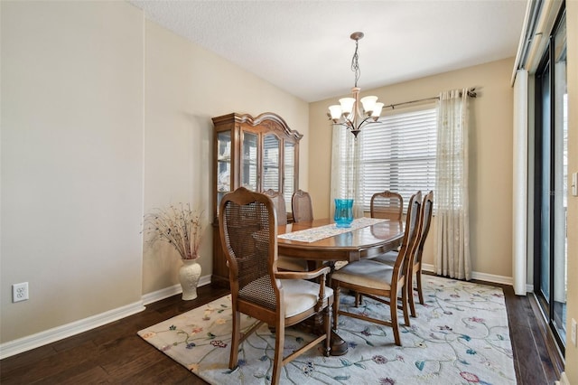 dining space featuring a notable chandelier, baseboards, and wood finished floors