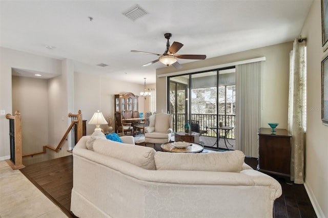 living area with ceiling fan with notable chandelier, visible vents, and baseboards