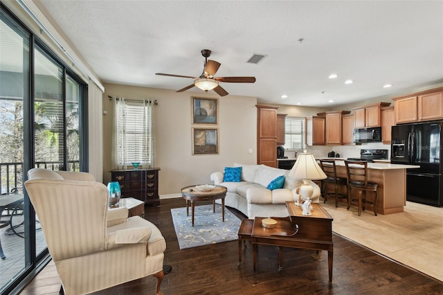 living area featuring ceiling fan, recessed lighting, visible vents, baseboards, and wood-type flooring