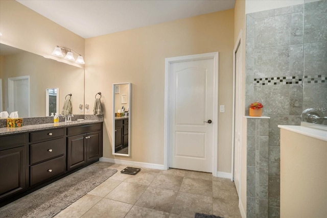 full bath featuring tile patterned flooring, walk in shower, vanity, and baseboards