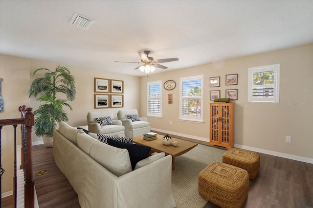 living room with dark wood-style floors, visible vents, ceiling fan, and baseboards