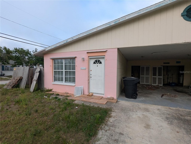 view of exterior entry featuring driveway, fence, and concrete block siding