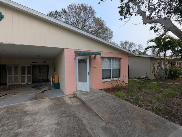 view of front of property featuring driveway, an attached carport, and concrete block siding