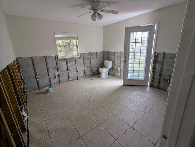 bathroom featuring ceiling fan, tile patterned flooring, toilet, a wainscoted wall, and tile walls