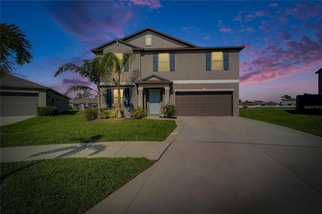 traditional home with a garage, concrete driveway, a yard, and stucco siding