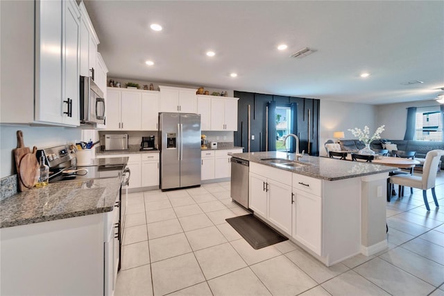 kitchen with open floor plan, appliances with stainless steel finishes, a sink, and white cabinets