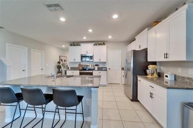 kitchen featuring light tile patterned floors, visible vents, a breakfast bar, stainless steel appliances, and a sink