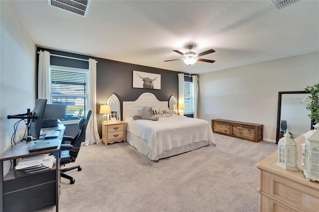 bedroom featuring visible vents, light carpet, and a textured ceiling