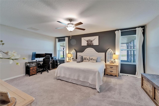 carpeted bedroom featuring a ceiling fan, visible vents, a textured ceiling, and baseboards