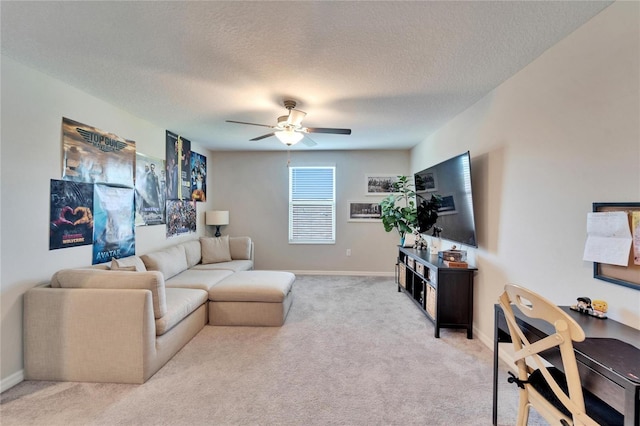 living area with a ceiling fan, light carpet, a textured ceiling, and baseboards