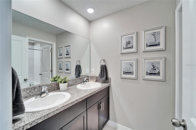 bathroom featuring double vanity, a sink, and baseboards