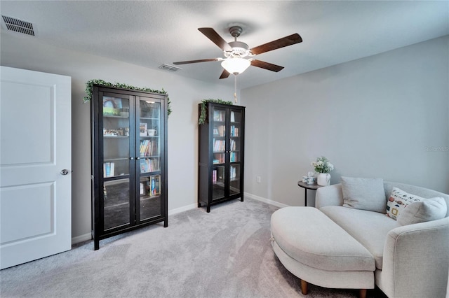 sitting room featuring baseboards, a ceiling fan, visible vents, and light colored carpet