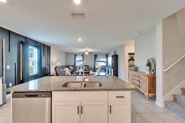 kitchen with visible vents, open floor plan, light stone counters, stainless steel dishwasher, and a sink
