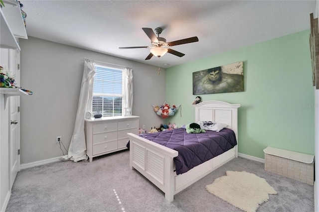 bedroom featuring ceiling fan, a textured ceiling, baseboards, and light carpet