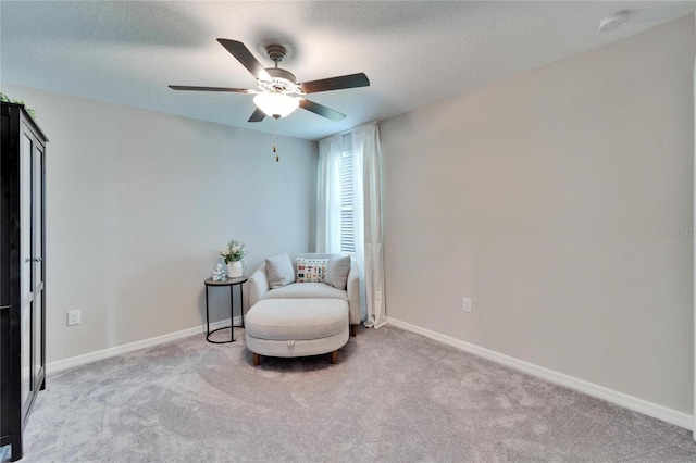 living area featuring baseboards, carpet floors, a textured ceiling, and ceiling fan