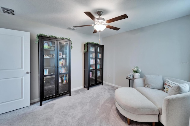 sitting room with visible vents, baseboards, light colored carpet, and a ceiling fan