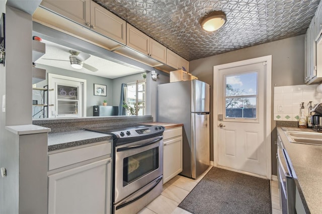 kitchen featuring an ornate ceiling, light tile patterned floors, decorative backsplash, appliances with stainless steel finishes, and a sink