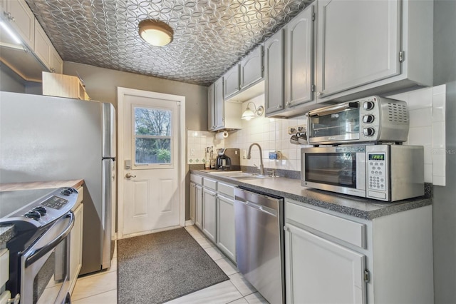 kitchen with dark countertops, an ornate ceiling, a sink, stainless steel appliances, and backsplash