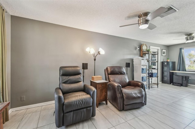 living area featuring a textured ceiling, baseboards, visible vents, and a ceiling fan