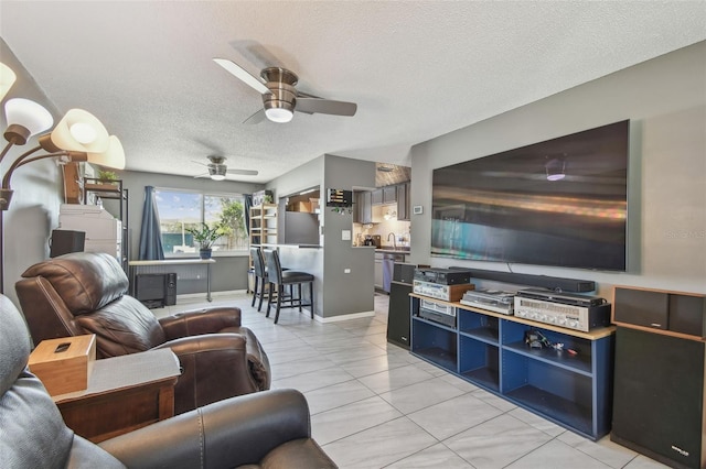 living area featuring ceiling fan, a textured ceiling, and light tile patterned floors