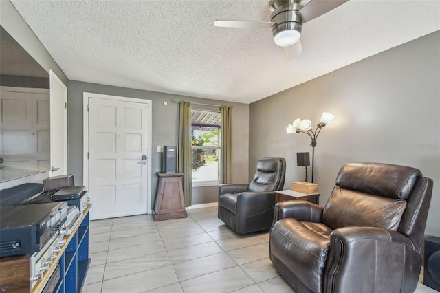 sitting room with a textured ceiling, light tile patterned flooring, and a ceiling fan